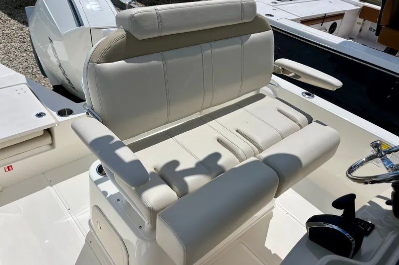 Slide: The Image of 2027 Boston Whaler 220 Dauntless boat seating area with beige upholstery and armrests. - 14