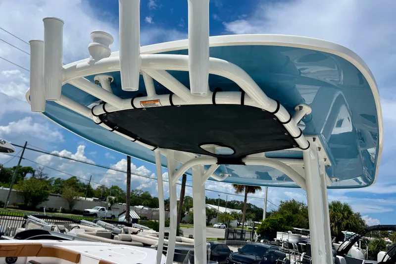 Slide: The Image of 2027 Boston Whaler 220 Dauntless boat with blue T-top and rod holders under a clear sky. - 15