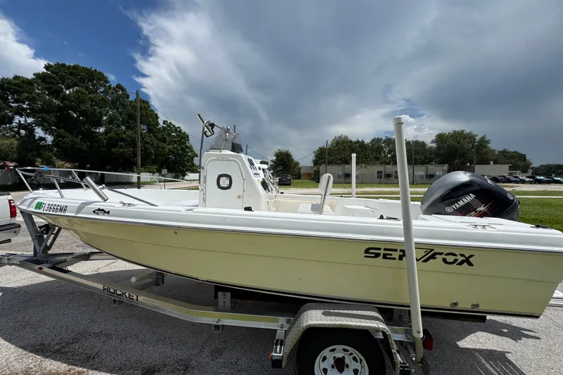 Slide: The Image of 2005 Sea Fox 197 Center Console boat on trailer, parked outdoors under cloudy sky. - 1
