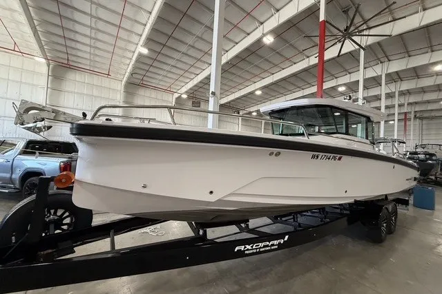 Slide: The Image of 2025 Axopar 29 XC Cross Cabin boat on trailer in indoor storage facility. - 2