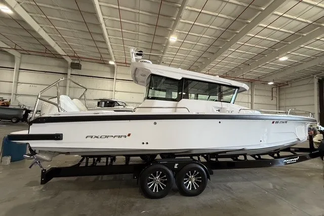 Slide: The Image of 2025 Axopar 29 XC Cross Cabin boat in a spacious indoor showroom. - 1