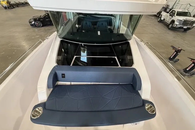 Slide: The Image of 2025 Axopar 29 XC Cross Cabin boat with blue seating and sleek design in a showroom. - 11