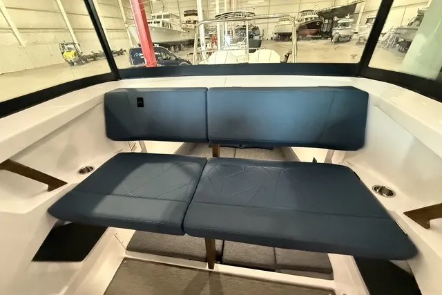 Slide: The Image of 2025 Axopar 29 XC Cross Cabin interior with blue seating in a boat showroom. - 15