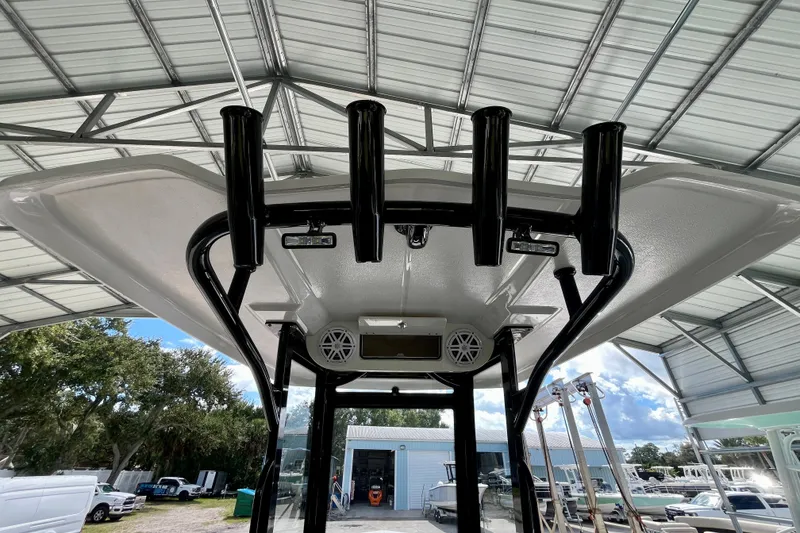 Slide: The Image of 2027 Robalo R230 Center Console boat under a metal canopy, showcasing rod holders and speakers. - 16