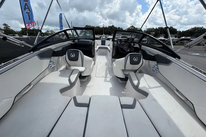 Slide: The Image of 2018 Scarab 195 G boat interior with white seating and steering wheel, under cloudy sky. - 14