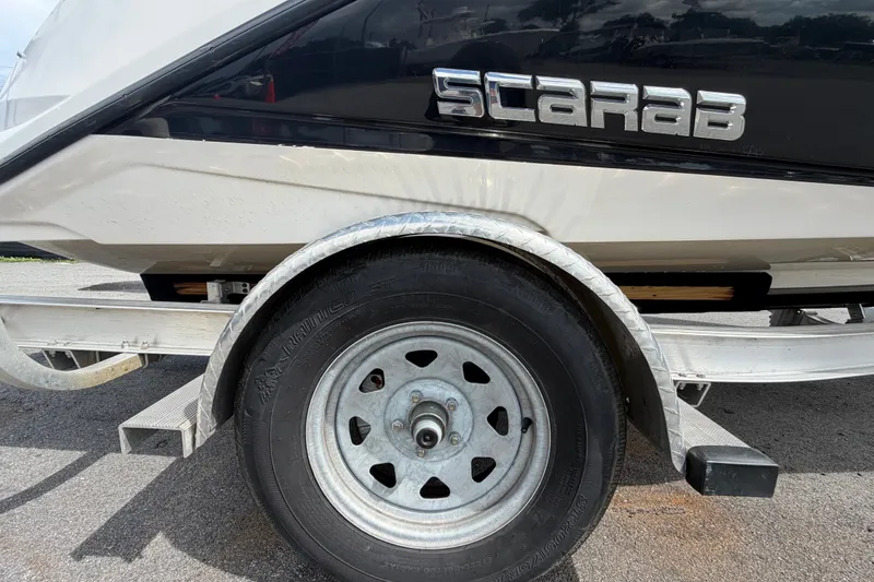 Slide: The Image of Trailer wheel of a 2018 Scarab 195 G boat on pavement. - 63