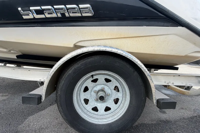 Slide: The Image of Trailer wheel of a 2018 Scarab 195 G boat on asphalt surface. - 62