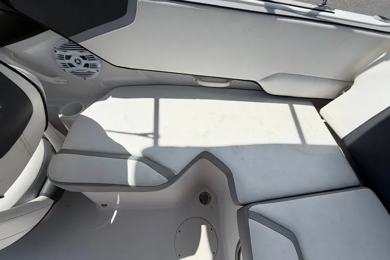 Slide: The Image of Interior seating of a 2018 Scarab 195 G boat, featuring white upholstery and speaker. - 49