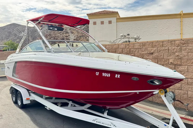 Slide: The Image of Red 2012 Cobalt 262 WSS boat on trailer, parked outdoors with scenic mountain backdrop. - 1