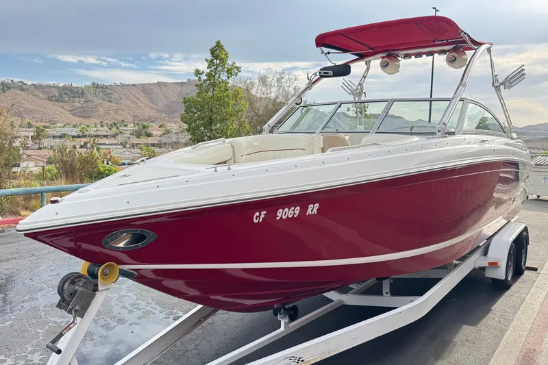 Slide: The Image of 2012 Cobalt 262 WSS boat with red hull on trailer, scenic background. - 3