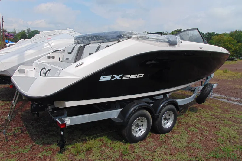 Slide: The Image of 2026 Yamaha Boats SX220 on trailer, sleek black and white design, parked outdoors. - 4