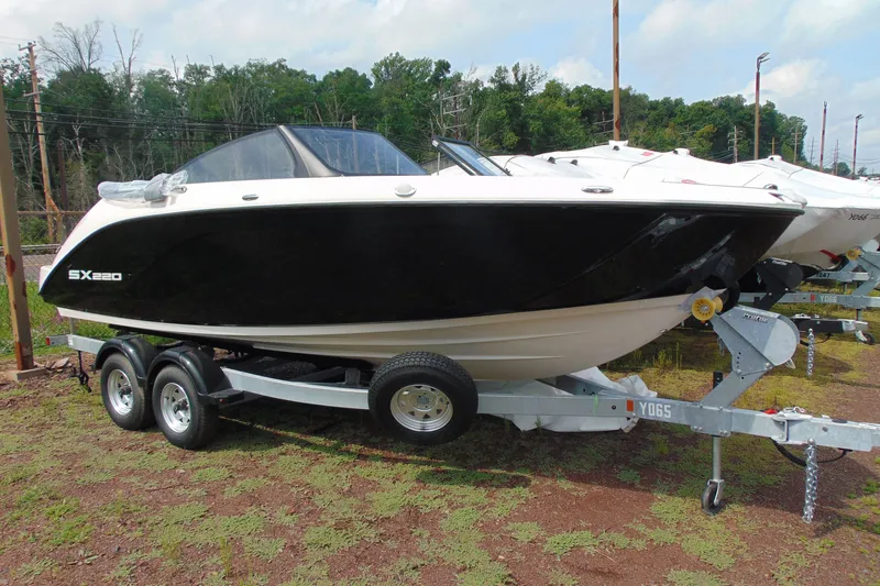 The Image of 2026 Yamaha Boats SX220 on trailer, black and white design, parked outdoors. - 2