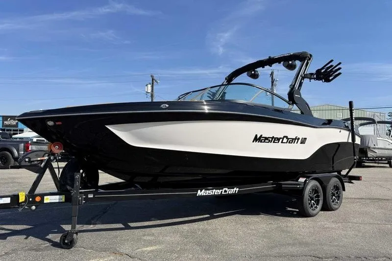 The Image of 2027 MasterCraft XT23 boat on trailer, black and white design, parked outdoors. - 0