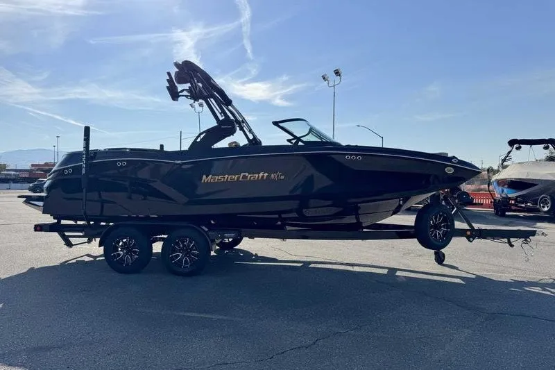 The Image of 2027 MasterCraft NXT22 boat on trailer in sunny outdoor setting. - 0