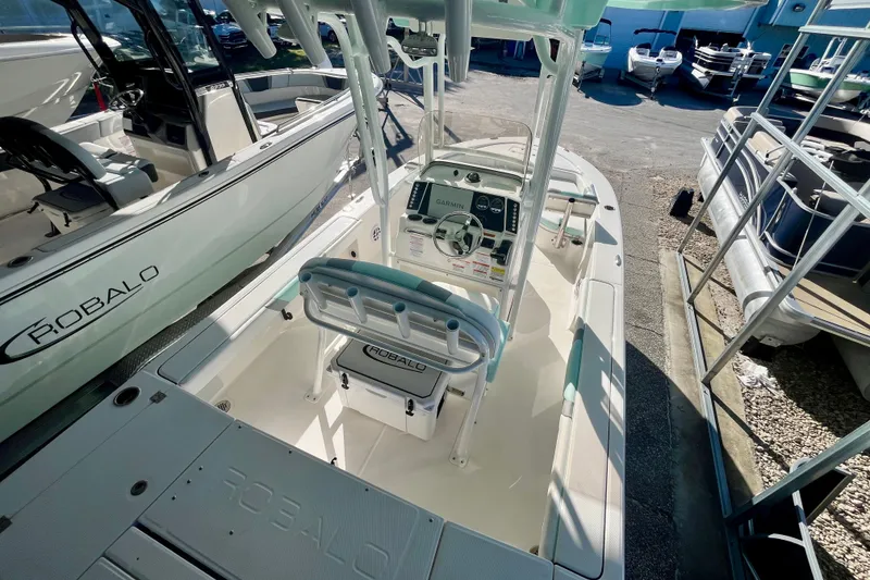 Slide: The Image of 2027 Robalo 226 Cayman boat interior with steering console and seating, docked outdoors. - 27