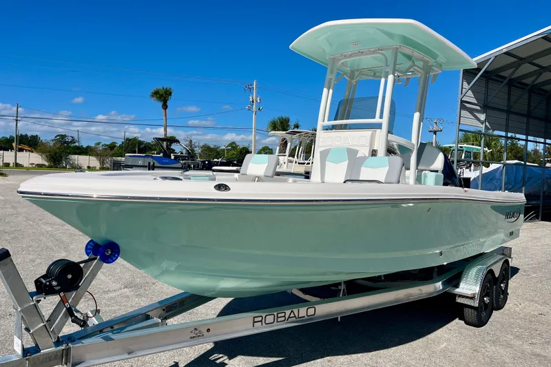Slide: The Image of 2027 Robalo 226 Cayman boat on trailer under clear blue sky. - 2