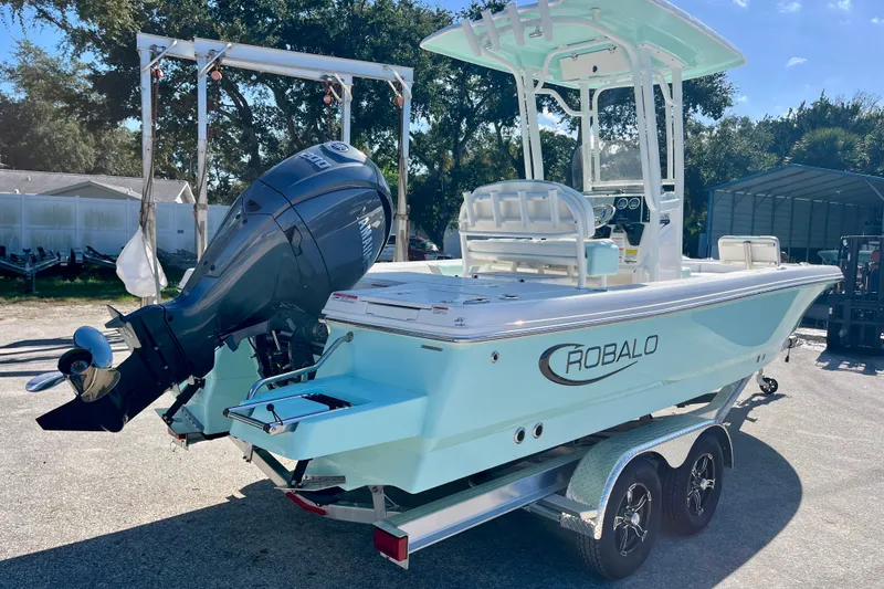 Slide: The Image of 2027 Robalo 226 Cayman boat on trailer with outboard motor in sunny outdoor setting. - 6