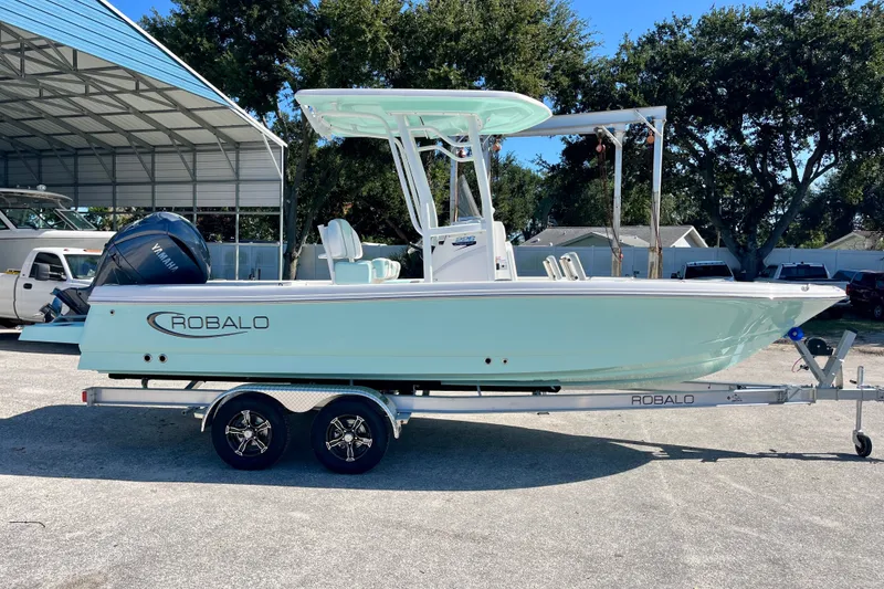 Slide: The Image of 2027 Robalo 226 Cayman boat on trailer, parked outdoors under a metal canopy. - 5
