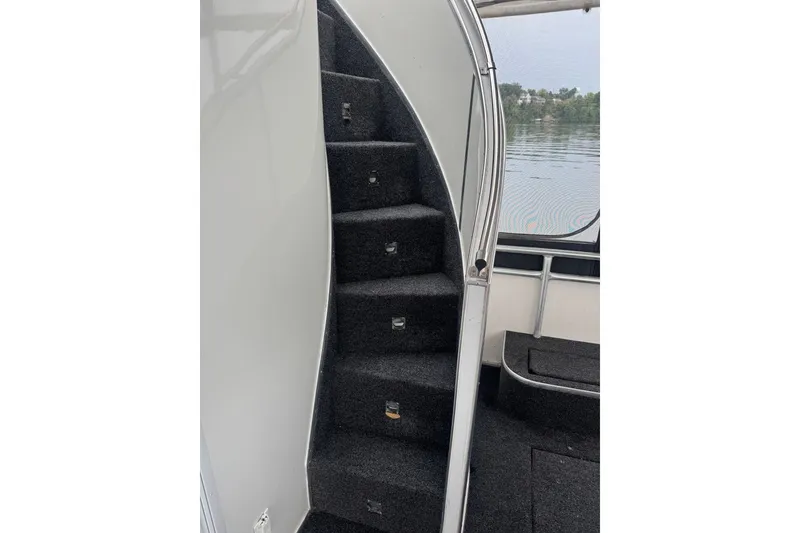 Slide: The Image of Curved staircase inside 2005 Sumerset 16'6" X 63 houseboat, with black carpet and metal railing. - 22