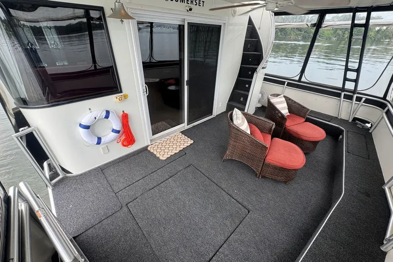 Slide: The Image of 2005 Sumerset houseboat deck with wicker chairs, red cushions, and a life preserver by the water. - 19
