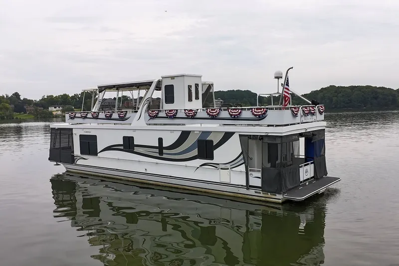 Slide: The Image of 2005 Sumerset 16'6" X 63 houseboat on a calm lake with decorative flags. - 5