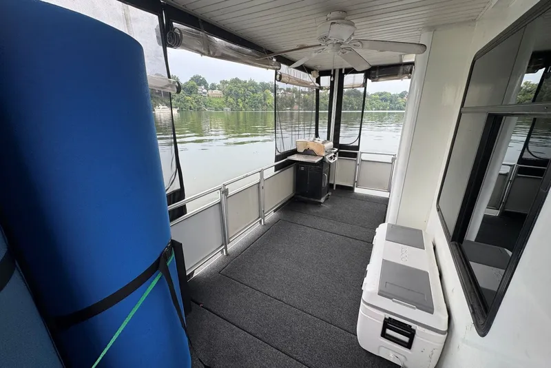 Slide: The Image of 2005 Sumerset houseboat interior with lake view, featuring a fan, cooler, and grill. - 92