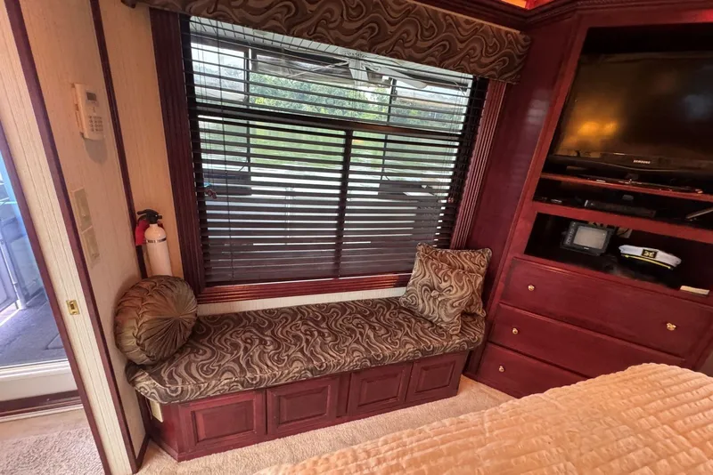 Slide: The Image of Interior of a 2005 Sumerset houseboat with cushioned seating, window blinds, and built-in entertainment unit. - 91