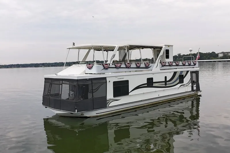 Slide: The Image of 2005 Sumerset 16'6" X 63 houseboat on calm water, decorated with patriotic bunting. - 2