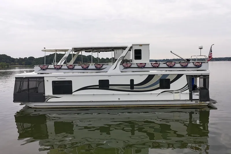 Slide: The Image of 2005 Sumerset 16'6" X 63 houseboat on calm lake with decorative flags. - 4