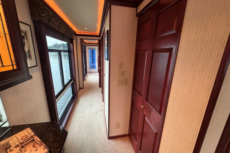 Slide: The Image of Luxurious hallway interior of a 2005 Sumerset houseboat, featuring elegant wood finishes and large windows. - 63