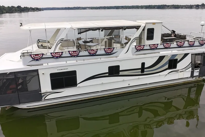 Slide: The Image of 2005 Sumerset 16'6" X 63 houseboat on calm lake with decorative banners. - 3