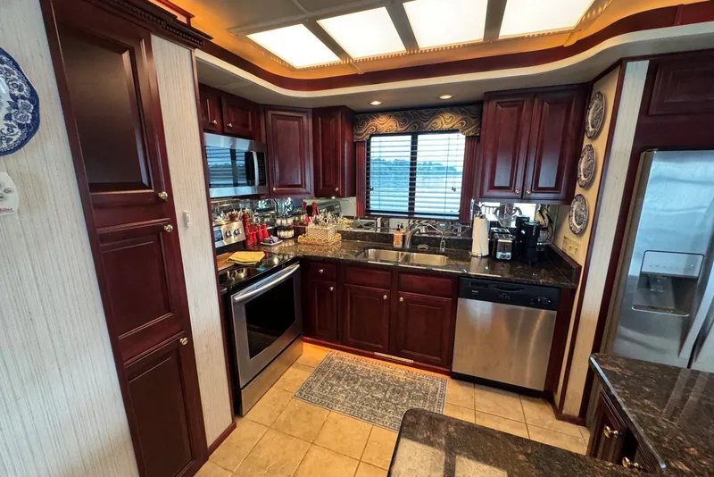 Slide: The Image of Luxurious kitchen in a 2005 Sumerset houseboat, featuring dark wood cabinets and modern appliances. - 53