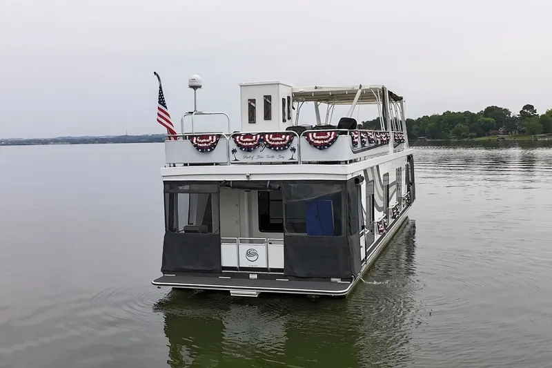 Slide: The Image of 2005 Sumerset houseboat on calm lake, decorated with patriotic bunting and American flag. - 9