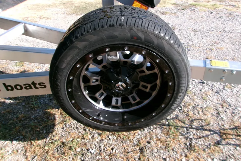 Slide: The Image of Trailer wheel of 2026 Xpress XR21 Bay boat on gravel surface. - 11