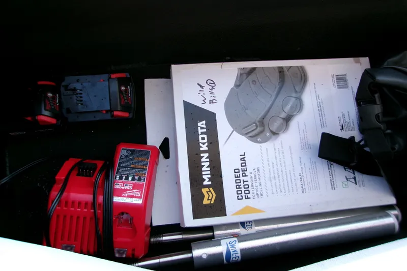 Slide: The Image of Storage compartment with Minn Kota foot pedal, Milwaukee charger, and accessories in Xpress XR21 Bay 2026. - 5