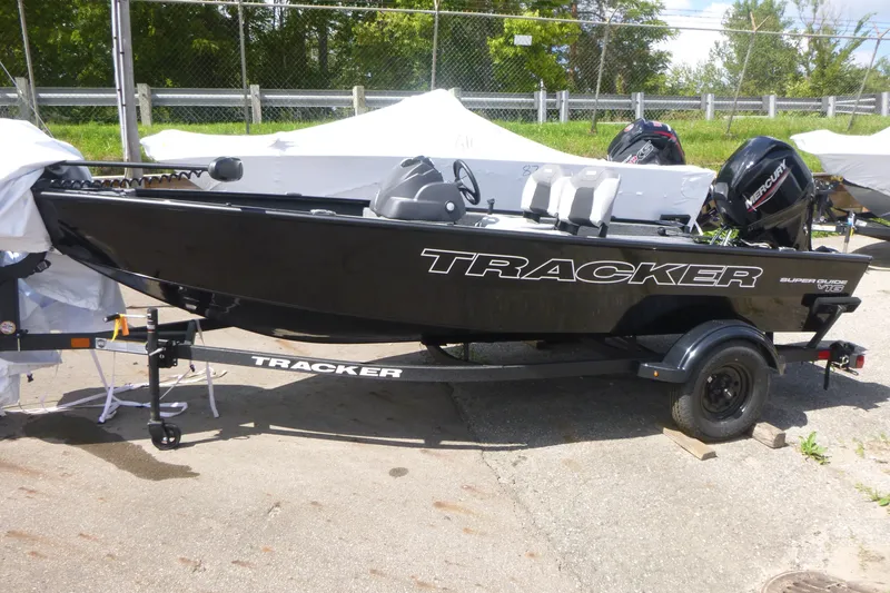 The Image of 2027 Tracker Super Guide V-16 SC boat on trailer, black exterior, parked outdoors. - 1