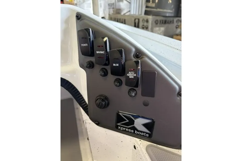 Slide: The Image of Control panel of 2027 Xpress H18 Bass boat with labeled switches and logo. - 14