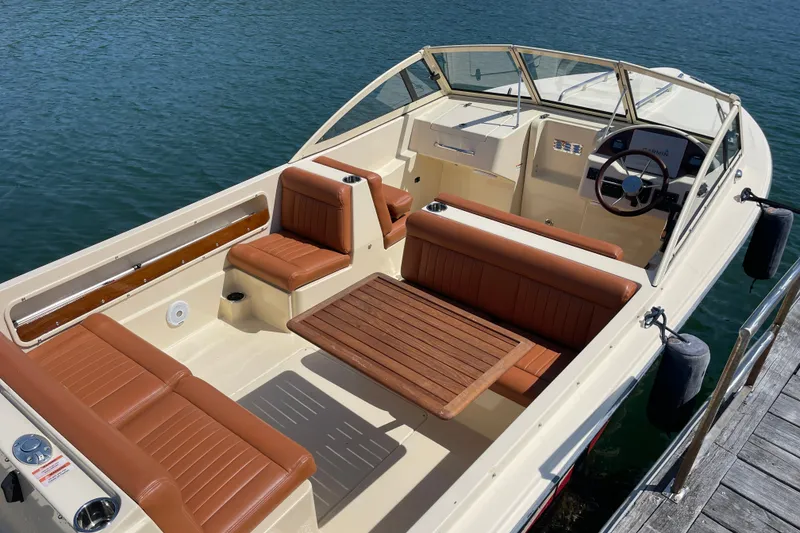 Slide: The Image of 2022 Rossiter 20 boat with brown leather seats and wooden table on calm water. - 24