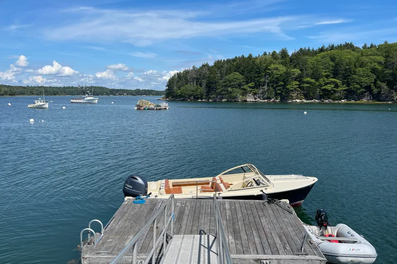 Slide: The Image of Docked 2022 Rossiter 20 boat on serene lake with lush forest backdrop. - 17