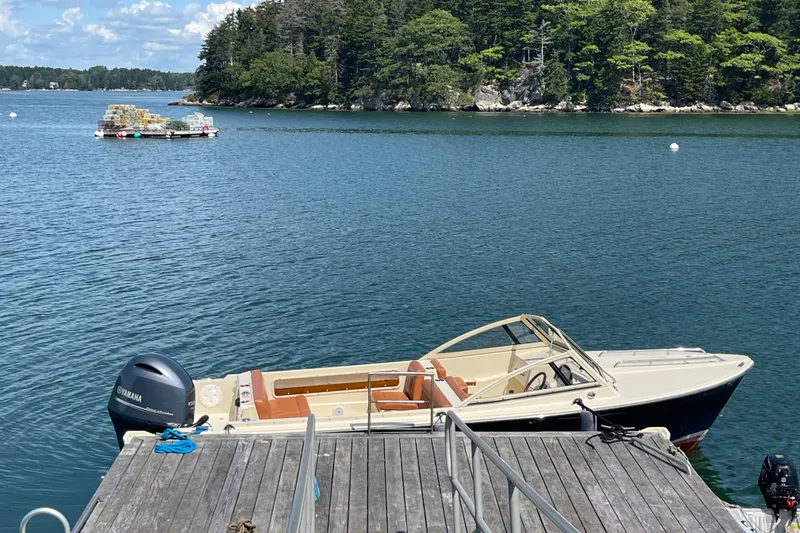 Slide: The Image of 2022 Rossiter 20 boat docked on a serene lake with lush forest backdrop. - 18