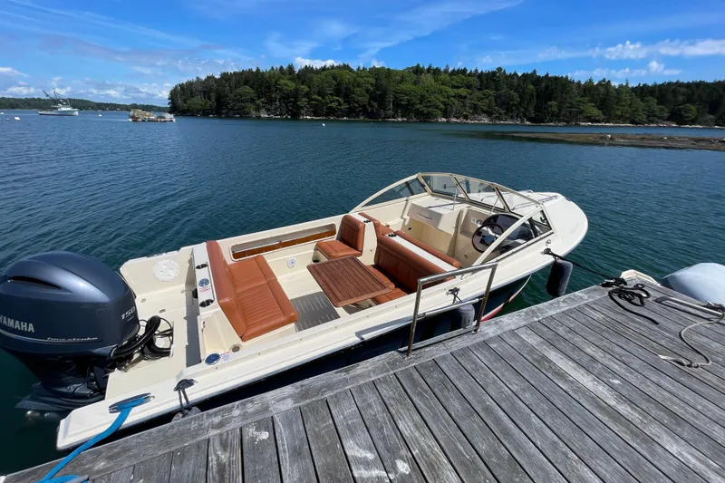Slide: The Image of 2022 Rossiter 20 boat docked on a serene lake with lush forest backdrop. - 20