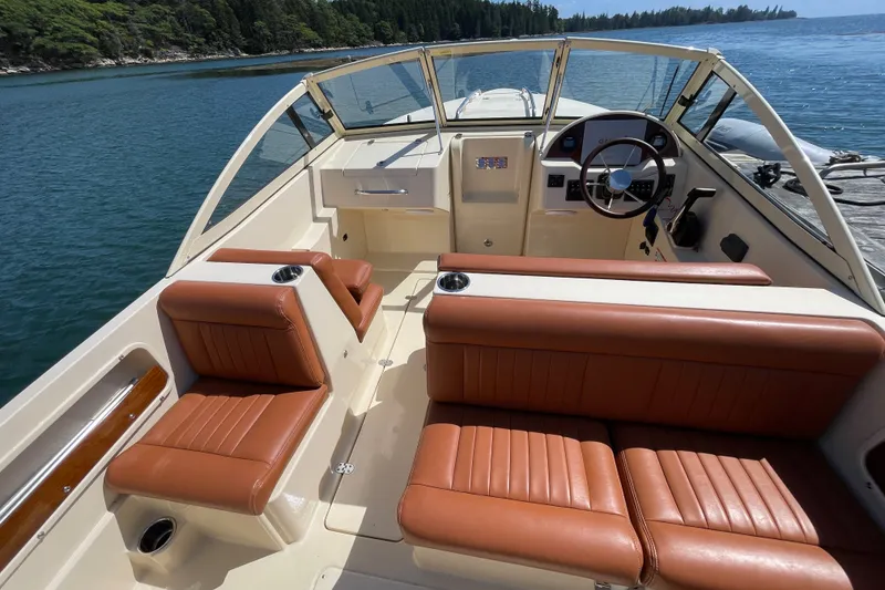 Slide: The Image of 2022 Rossiter 20 boat interior with tan leather seats, steering wheel, and scenic water view. - 32