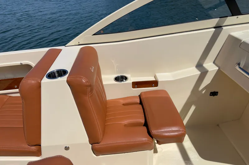 Slide: The Image of 2022 Rossiter 20 boat interior with tan leather seats and cup holders by the water. - 37