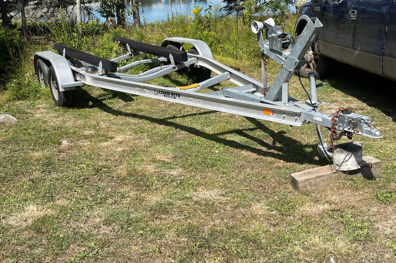 Slide: The Image of Boat trailer parked on grass, near a lake, beside a vehicle. - 59