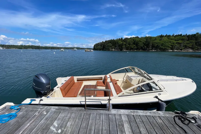 Slide: The Image of 2022 Rossiter 20 boat docked on a scenic lake with lush green shoreline. - 19