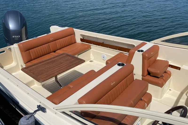 Slide: The Image of 2022 Rossiter 20 boat interior with tan leather seating and wooden table on calm water. - 27