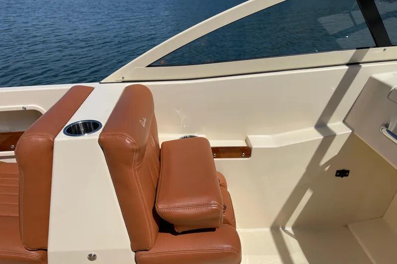 Slide: The Image of 2022 Rossiter 20 boat interior with tan leather seats and cup holder by the water. - 36