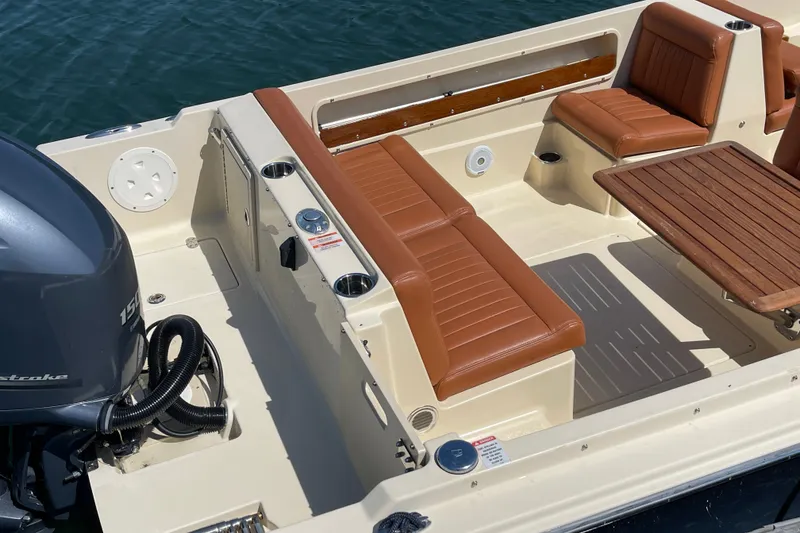 Slide: The Image of 2022 Rossiter 20 boat interior with tan leather seats and wooden table, featuring a 150 HP outboard motor. - 22