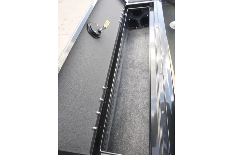 Slide: The Image of 2027 Tracker Targa V-19 Combo boat storage compartment with rod holders and carpeted interior. - 16