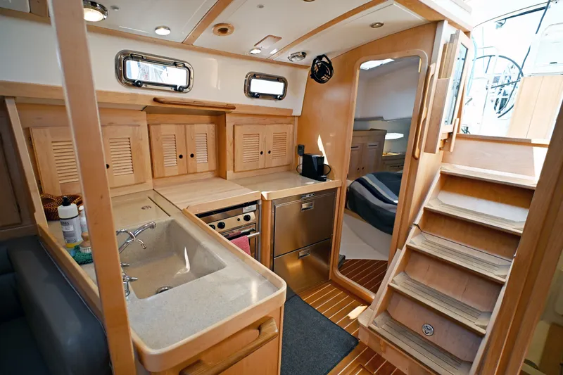 Slide: The Image of 2024 Tartan 395 yacht interior with modern kitchen, wooden cabinetry, and cozy sleeping area. - 9